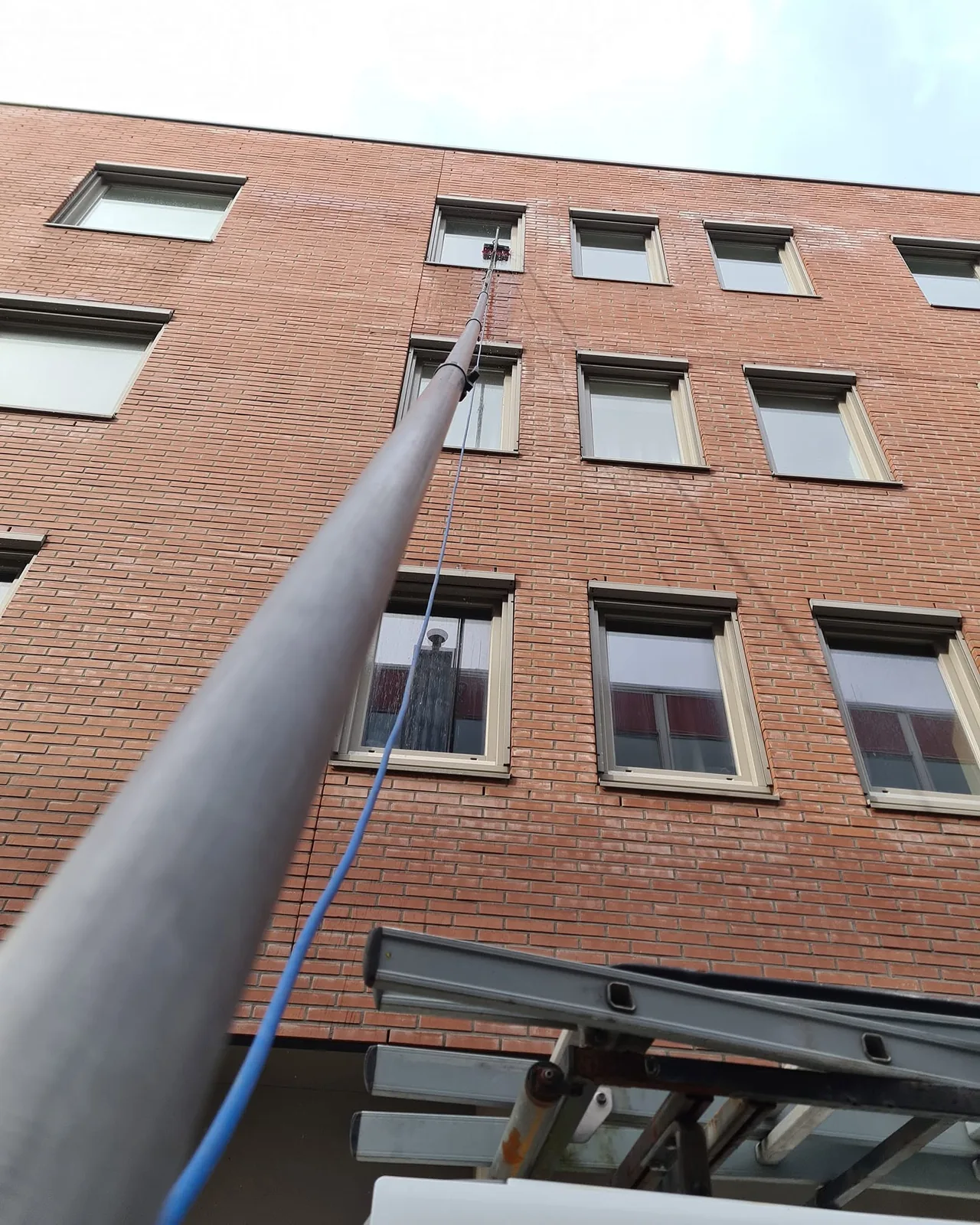 Glasbewassing aan een woongebouw met een telescopische steel
